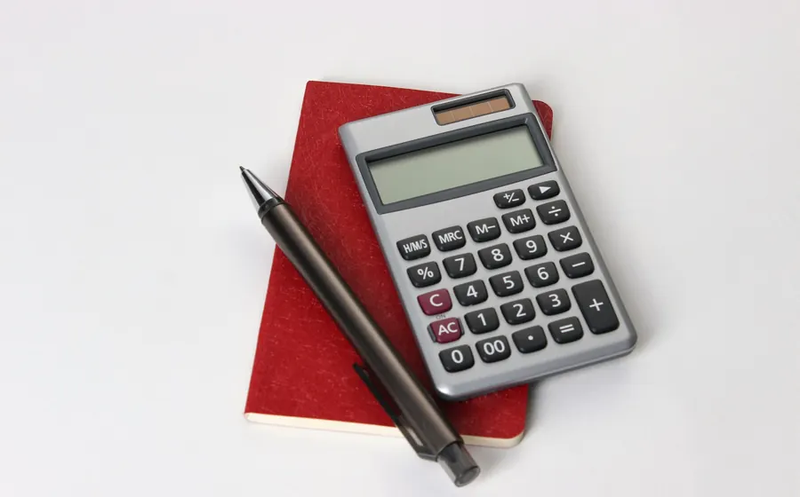 Calculadora y lápiz sobre una libreta roja para preparar un presupuesto