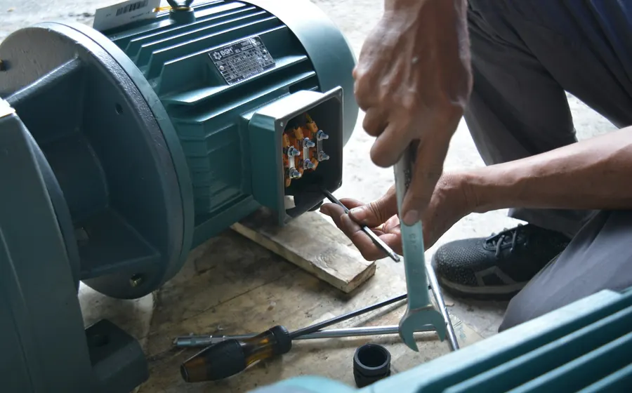 Técnico ajustando con una llave la caja de conexiones de un motor eléctrico