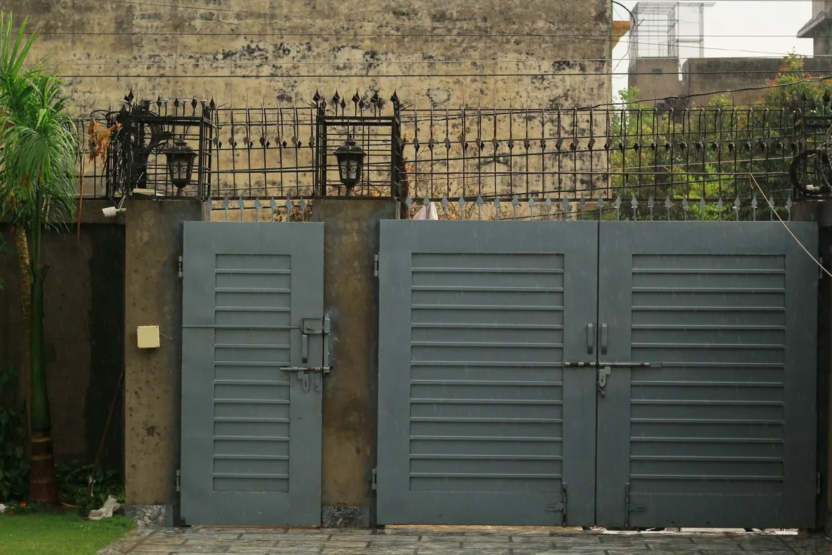 Portón metálico gris de dos hojas en el acceso de una casa