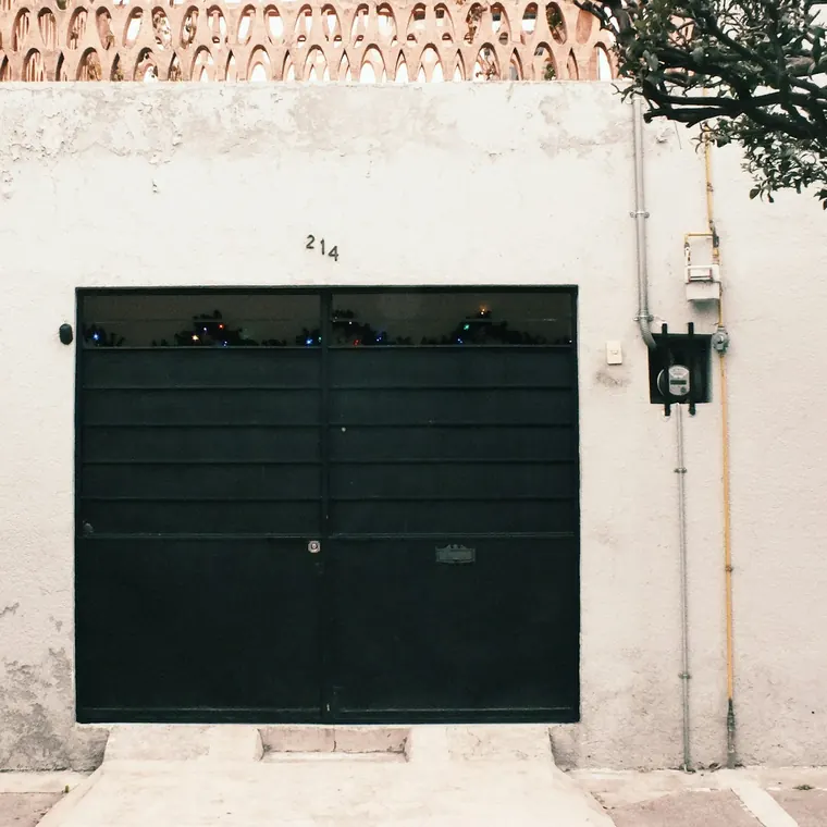 Portón de garaje negro en una fachada blanca